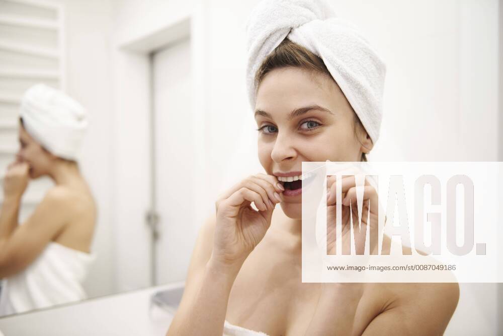 Portrait of young woman using dental floss in bathroom model released Symbolfoto property released ABIF00989