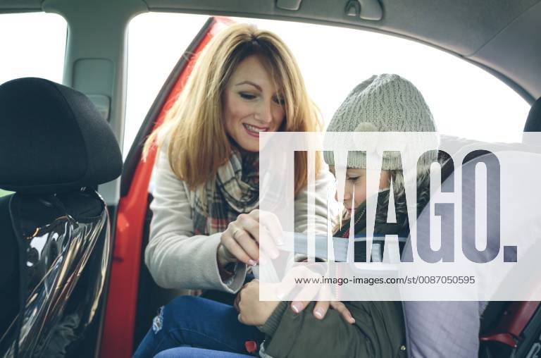 Mother fastening little girl with safety seat belt in a car model released Symbolfoto DAPF00807