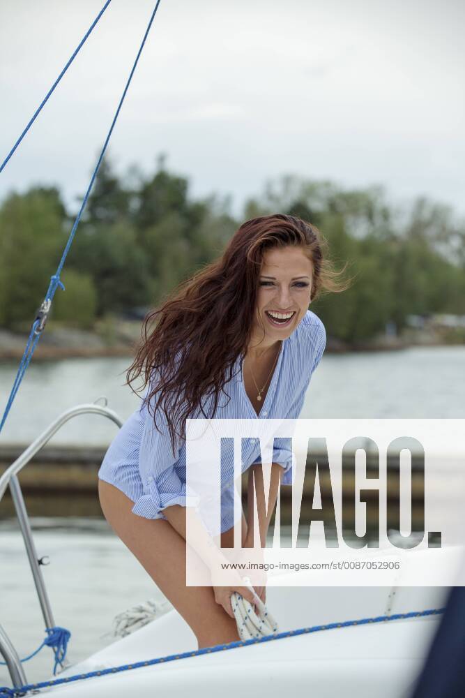 Woman on sailing boat holing rope, laughing model released Symbolfoto property released JZF00013