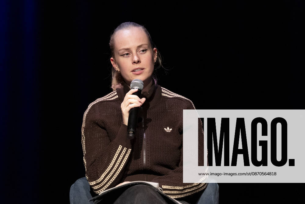 Poetry artist and author Clara LOESEL LÖSEL, focused and pensive, during her reading—a preview of her new book, *Ich dachte, sowas fühle nur ich*—seated with a microphone; single frame, single photo, at the Theater am Tanzbrunnen, Cologne, on October 23, 2026