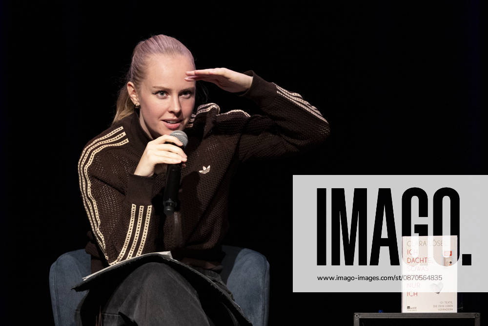 Poetry artist and author Clara LOESEL LÖSEL gazes searchingly into the audience during her reading—a preview show for her new book, *Ich dachte, sowas fühle nur ich*—seated with a microphone, a single frame, a single photo, at the Theater am Tanzbrunnen, Cologne, on October 23, 2026