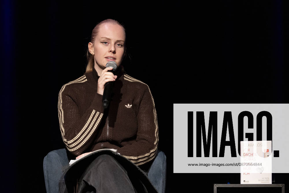 Poetry artist and author Clara LOESEL LÖSEL, serious and focused during her reading—a preview event for her new book, *Ich dachte, sowas fühle nur ich*—seated with a microphone; single frame, single photo, at the Theater am Tanzbrunnen, Cologne, on October 23, 2026