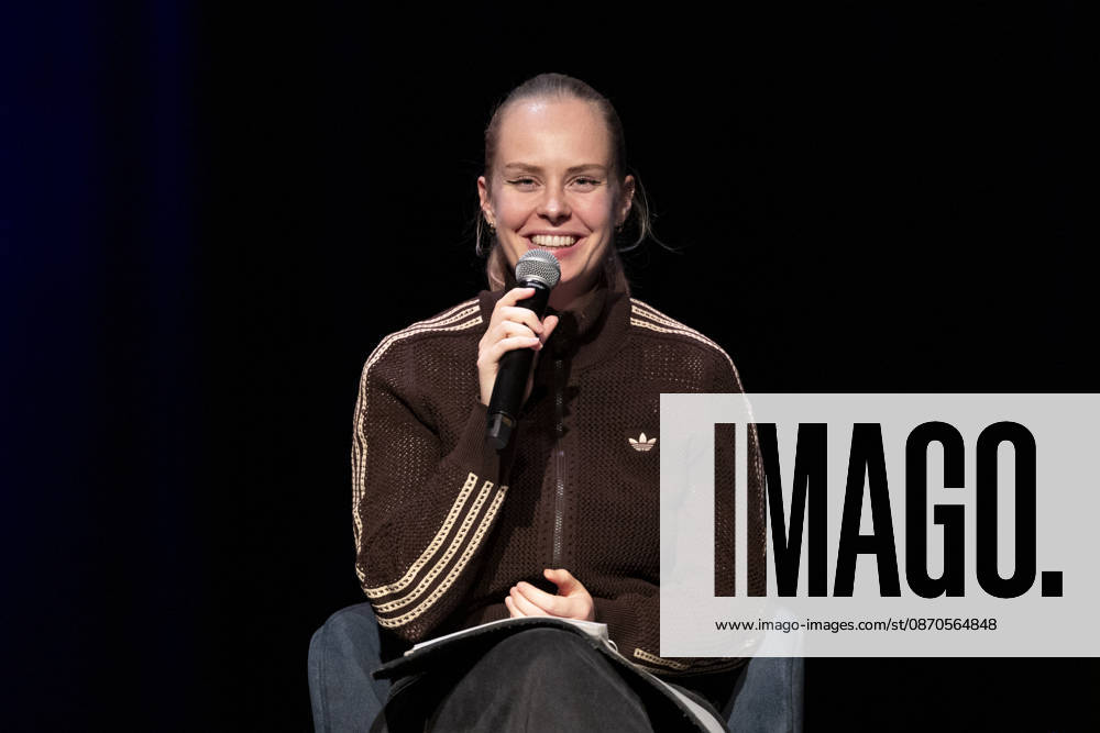 Poetry artist and author Clara LOESEL LÖSEL laughing during her reading, a preview event for her new book *Ich dachte, sowas fühle nur ich* (I Thought I Was the Only One Who Felt That Way), seated with a microphone; single frame, single photo, at the Theater am Tanzbrunnen, Cologne, on October 23, 2026