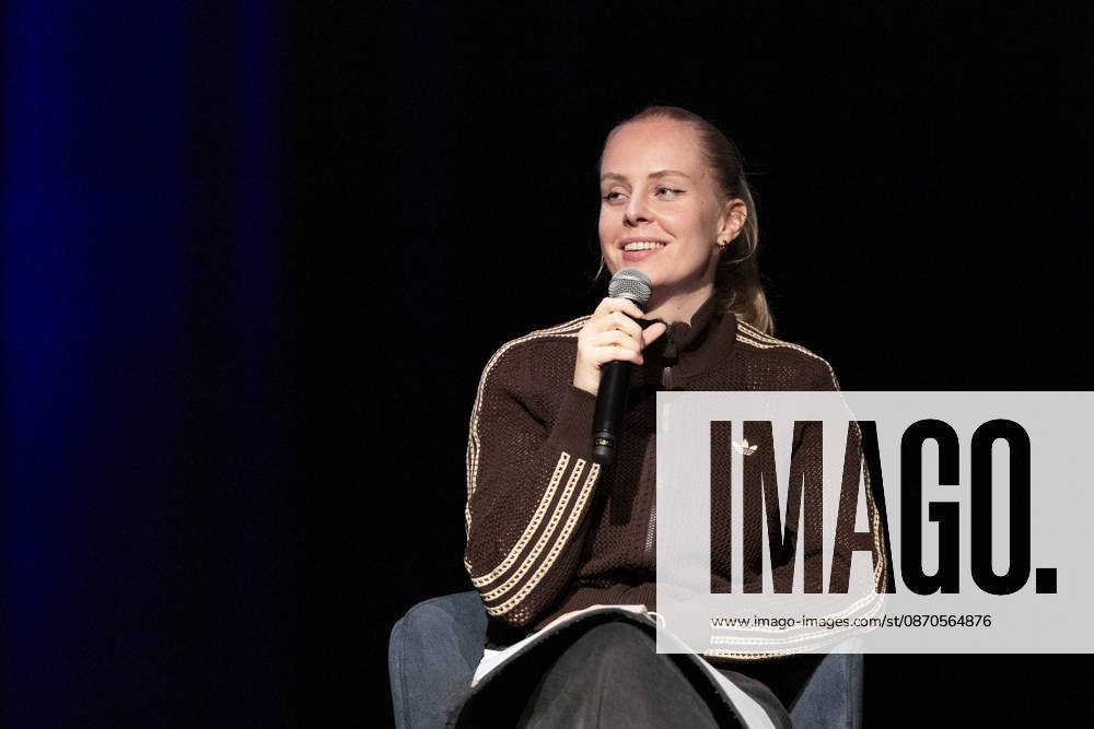 Poetry artist and author Clara LOESEL LÖSEL laughing during her reading, a preview show for her new book *Ich dachte, sowas fühle nur ich* (I Thought I Was the Only One Who Felt That Way), seated with a microphone; single frame, single photo, at the Theater am Tanzbrunnen, Cologne, on October 23, 2026