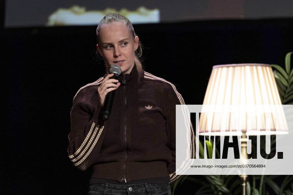 Poetry artist and author Clara LOESEL LÖSEL speaks intently during her reading—a preview of her new book, *Ich dachte, sowas fühle nur ich*—standing with a microphone, in a single frame, a single photograph, at the Theater am Tanzbrunnen, Cologne, on October 23, 2026