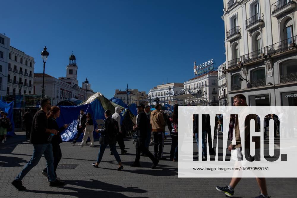 People walk in front of the tents of an encampment for decent housing, set up at Puerta del Sol..Tents remain set up by housing rights activists, who organized the occupation of the square in response to the eviction of MaricarmenÃ¢â‚¬a woman in her eightiesÃ¢â‚¬from her home, carried out by a real estate investment fund. Madrid Spain - ZUMAs197 20261023_aaa_s197_154