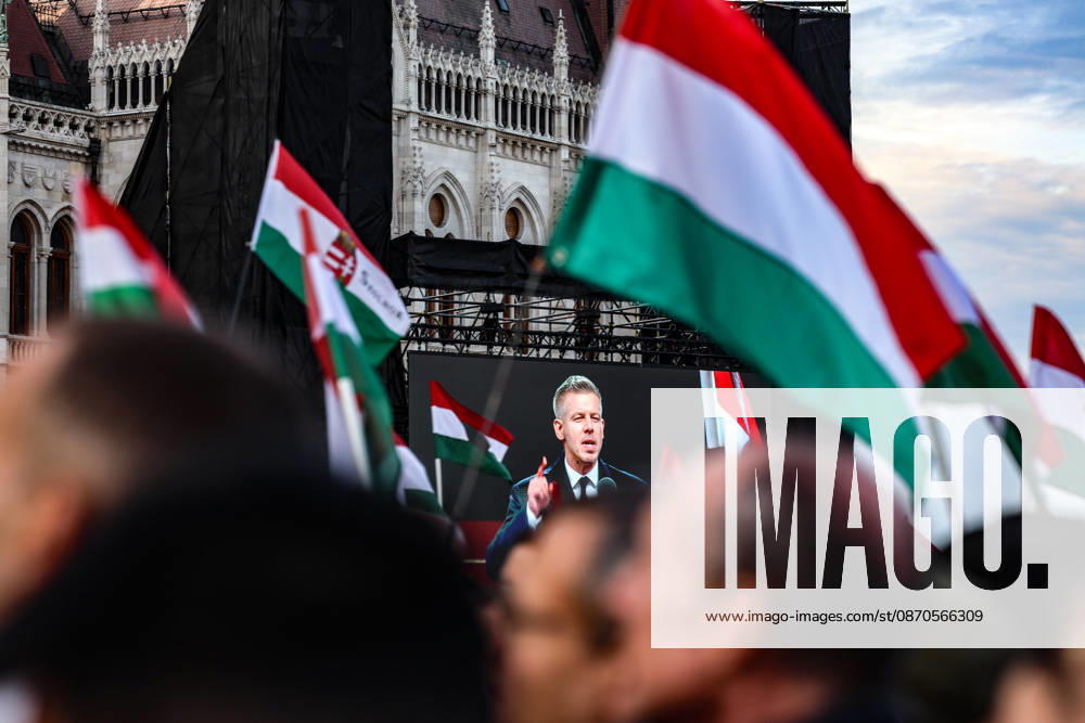 Hungarian Prime Minister Peter MAGYAR appears on a giant screen addressing crowds surrounded by Hungarian flags at Kossuth Square outside Parliament, delivering his first October 23 commemorative speech as prime minister on the 70th anniversary of the 1956 Hungarian Revolution. Budapest Hungary - ZUMAo116 20261023_znp_o116_017