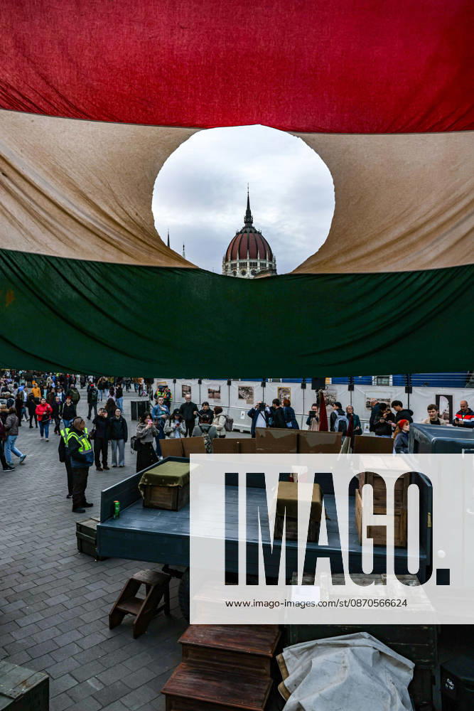 The dome of the Hungarian Parliament is seen through the cut-out center of a large Hungarian revolutionary flag as visitors gather during commemorations marking the 70th anniversary of the 1956 Hungarian Revolution. The hole in the flag symbolizes the removal of the communist-era coat of arms during the uprising against Soviet-backed rule. Budapest Hungary - ZUMAo116 20261023_znp_o116_087