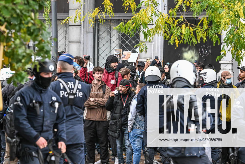 Riot police officers in protective gear surround a group of demonstrators, some wearing face coverings and others unmasked, during student protests in central Brussels, Belgium, on 24 October 2026. Several people film the police operation with their mobile phones as officers confront the protesters amid unrest in the city centre.