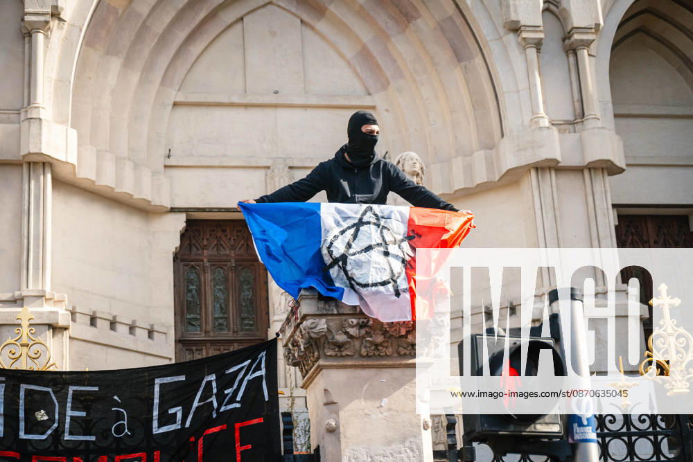 Marseille France Street Protests A protester holds a French flag atop a monument during unrest in Marseille, France on October 24, 2026. Authorities deployed around 70,000 security personnel across France for renewed protests over the cost of living, after unrest a week earlier saw public buildings damaged, hundreds of shops looted and about 2,700 people arrested. Marseille Provence-Alpes-CÃ te France
