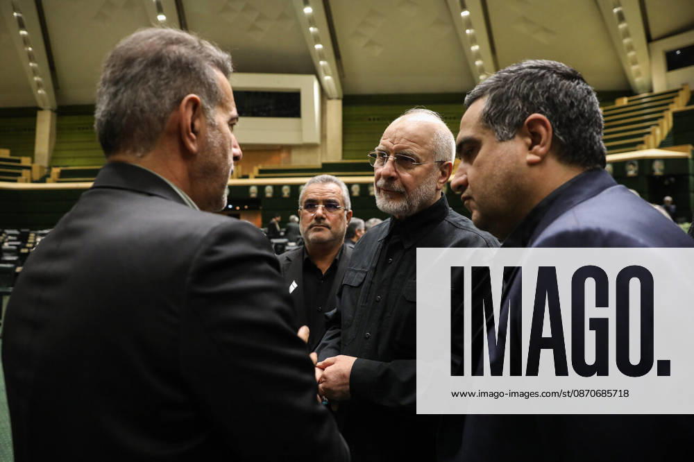 Mohammad Bagher Ghalibaf speaks with two suited men standing close to him among the green seats of parliament at the Islamic Consultative Assembly in Tehran, Iran, on October 25, 2026. Parliamentary reports said more than two-thirds of lawmakers joined the October 25 open sitting of the Islamic Consultative Assembly, attending either in person or remotely. Tehran Iran - ZUMAi98_ 20261025_zih_i98_031