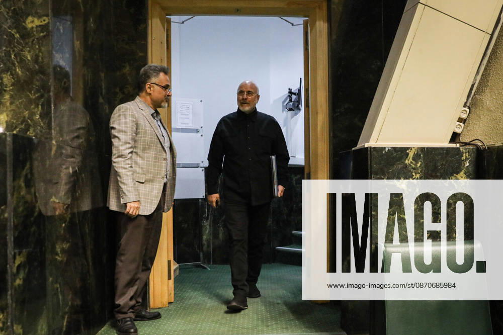 Mohammad Bagher Ghalibaf enters the chamber through a doorway as a man in a beige jacket stands to one side at the Islamic Consultative Assembly in Tehran, Iran, on October 25, 2026. The Iranian parliament held a hybrid open sitting, with some lawmakers attending in the Tehran chamber and others participating remotely, according to parliamentary reports. Tehran Iran - ZUMAi98_ 20261025_zih_i98_064