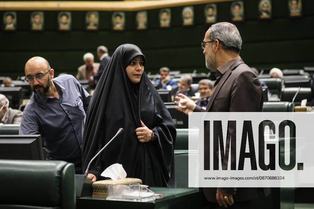 A woman in a black chador talks with a gray-haired man as another member stands nearby in the chamber at the Islamic Consultative Assembly in Tehran, Iran, on October 25, 2026. The Iranian parliament held a hybrid open sitting, with some lawmakers attending in the Tehran chamber and others participating remotely, according to parliamentary reports. Tehran Iran - ZUMAi98_ 20261025_zih_i98_082