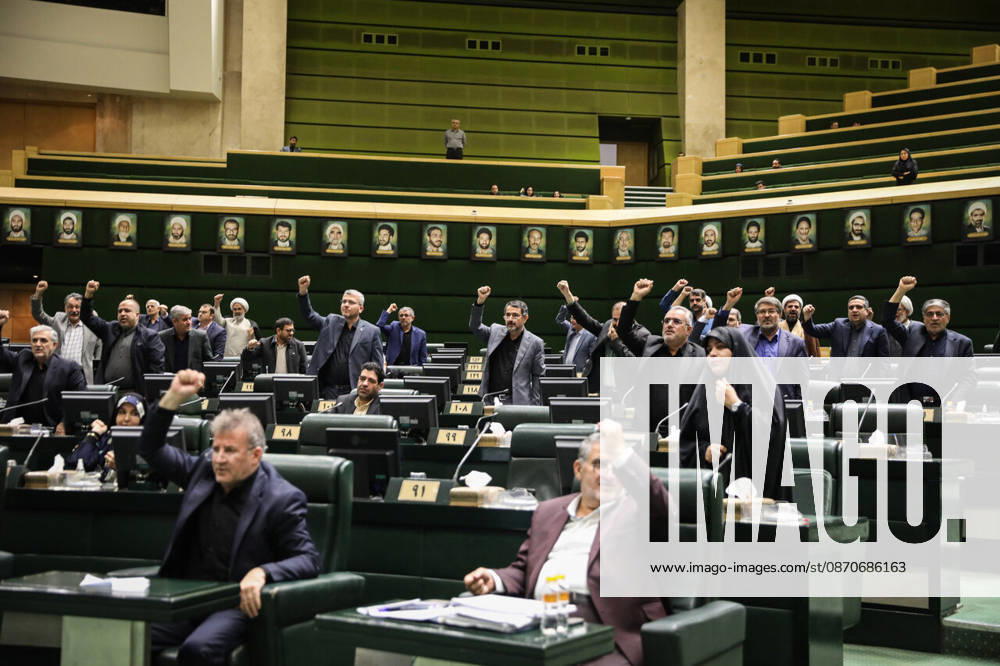 Rows of lawmakers raise their hands while others remain seated beneath portraits on the chamber wall at the Islamic Consultative Assembly in Tehran, Iran, on October 25, 2026. Speaker Mohammad Bagher Ghalibaf chaired the October 25 session, which combined physical attendance at the Islamic Consultative Assembly with participation by video link. Tehran Iran - ZUMAi98_ 20261025_zih_i98_101