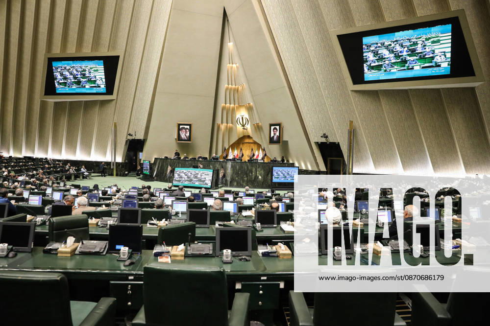 Two screens high on the walls display the ongoing sitting above the widely spaced parliamentary seating at the Islamic Consultative Assembly in Tehran, Iran, on October 25, 2026. The Islamic Consultative Assembly resumed an open sitting in its Tehran chamber with a mix of in-person and remote participation, according to parliamentary reporting. Tehran Iran - ZUMAi98_ 20261025_zih_i98_107