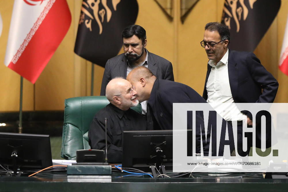 Mohammad Bagher Ghalibaf talks with a man leaning toward his chair while two other officials stand behind the presiding desk at the Islamic Consultative Assembly in Tehran, Iran, on October 25, 2026. Parliamentary reports said more than two-thirds of lawmakers joined the October 25 open sitting of the Islamic Consultative Assembly, attending either in person or remotely. Tehran Iran - ZUMAi98_ 20261025_zih_i98_108