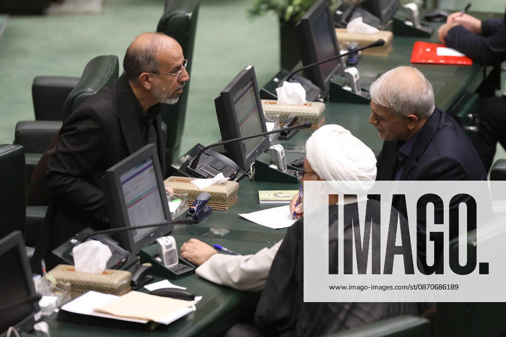 Three male lawmakers confer across a row of desks fitted with desktop screens and microphones at the Islamic Consultative Assembly in Tehran, Iran, on October 25, 2026. Parliamentary reports said more than two-thirds of lawmakers joined the October 25 open sitting of the Islamic Consultative Assembly, attending either in person or remotely. Tehran Iran - ZUMAi98_ 20261025_zih_i98_111