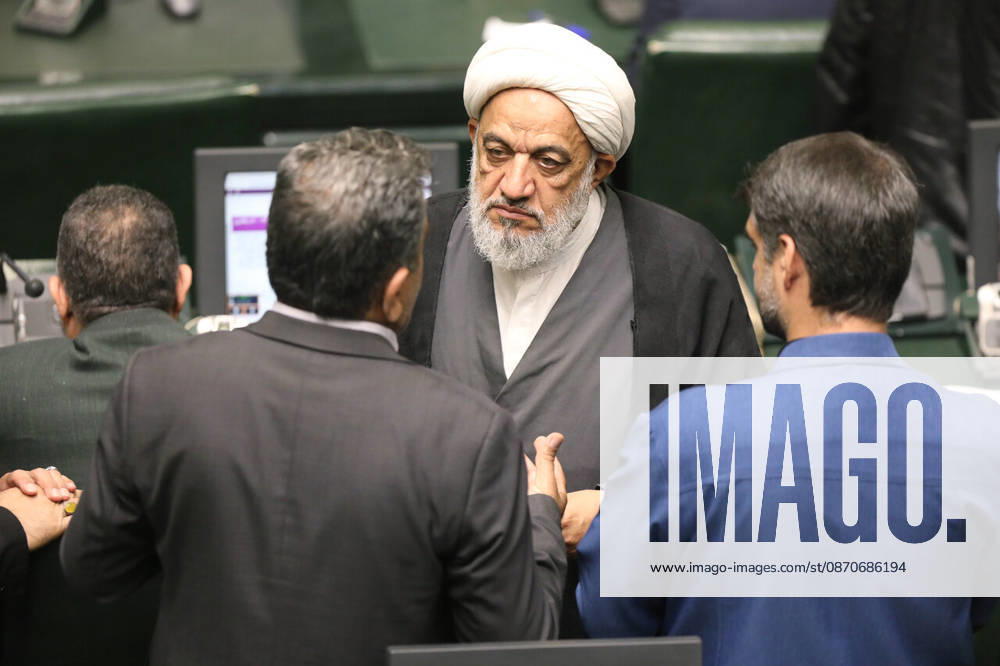 A gray-bearded cleric in a white turban listens to three suited lawmakers gathered around his desk at the Islamic Consultative Assembly in Tehran, Iran, on October 25, 2026. The Iranian parliament held a hybrid open sitting, with some lawmakers attending in the Tehran chamber and others participating remotely, according to parliamentary reports. Tehran Iran - ZUMAi98_ 20261025_zih_i98_114