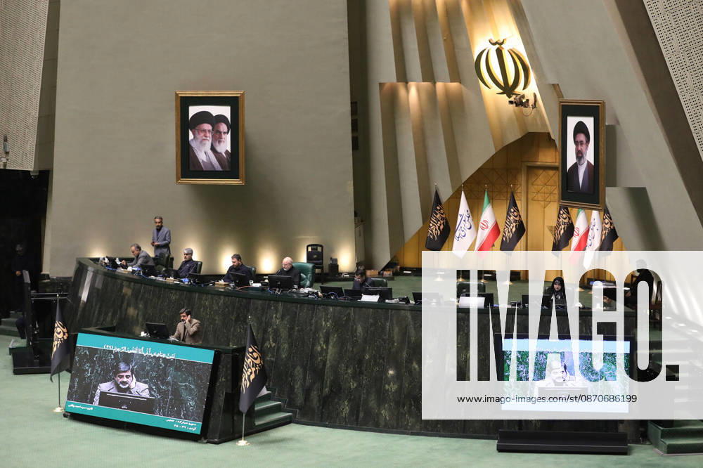 The raised parliamentary dais is seen from the chamber floor beneath Iranian flags and two framed portraits at the Islamic Consultative Assembly in Tehran, Iran, on October 25, 2026. Speaker Mohammad Bagher Ghalibaf chaired the October 25 session, which combined physical attendance at the Islamic Consultative Assembly with participation by video link. Tehran Iran - ZUMAi98_ 20261025_zih_i98_117