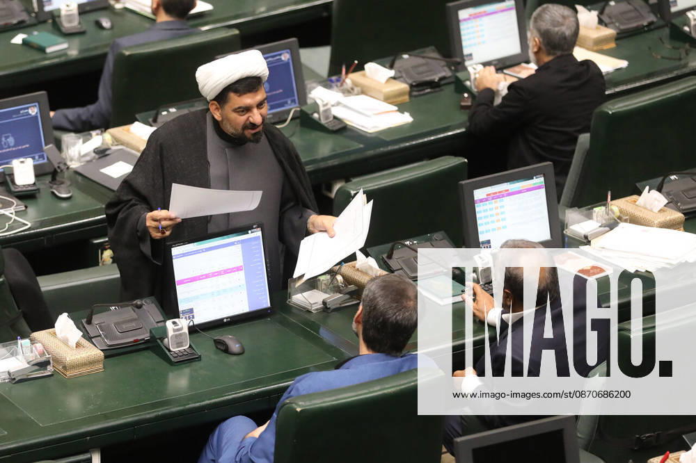 A white-turbaned cleric stands at his desk reading a sheet of paper as two seated lawmakers look toward him at the Islamic Consultative Assembly in Tehran, Iran, on October 25, 2026. Speaker Mohammad Bagher Ghalibaf chaired the October 25 session, which combined physical attendance at the Islamic Consultative Assembly with participation by video link. Tehran Iran - ZUMAi98_ 20261025_zih_i98_118