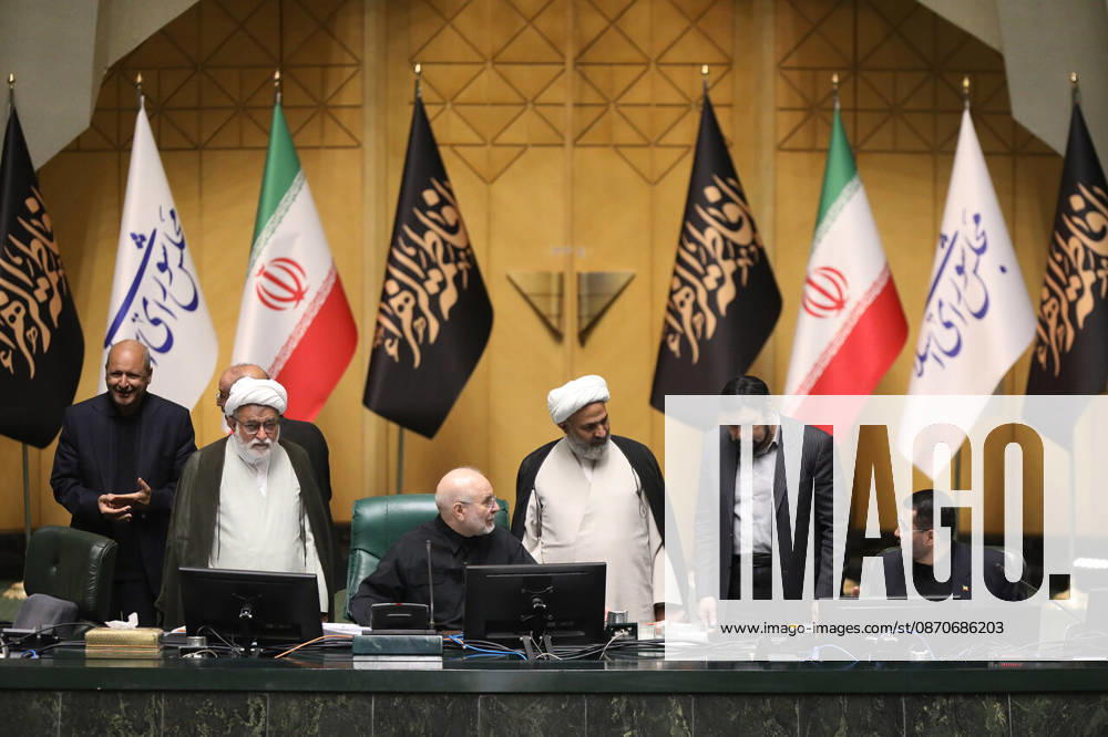 Two clerics in white turbans stand with other officials near Mohammad Bagher Ghalibaf at the presiding desk at the Islamic Consultative Assembly in Tehran, Iran, on October 25, 2026. The Islamic Consultative Assembly resumed an open sitting in its Tehran chamber with a mix of in-person and remote participation, according to parliamentary reporting. Tehran Iran - ZUMAi98_ 20261025_zih_i98_121