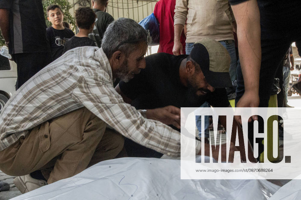 Gaza Israeli University Strike 2026 Two Palestinian men crouch beside a white body bag ahead of a funeral in Gaza City, Palestine, on October 25, 2026. According to information provided by local sources, three Islamic University guards, Ashraf Dahlan, Shadi Abu Ataya and Sami Baroud, were killed and others injured in an Israeli strike on the university campus in western Gaza City. Palestinian media reported that a second drone strike hit the campus after an earlier attack injured several people and prompted the university to suspend activities. Gaza Gaza Strip Palestinian Territories