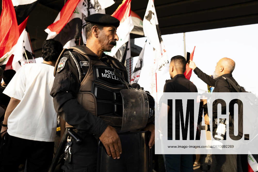 Najaf Iraq October Protest A police officer stands near demonstrators during a protest in Najaf, Iraq on October 25, 2026. The protest marked the seventh anniversary of the October 2019 protest movement, with participants calling for political reform, anti-corruption measures, improved public services and more jobs. Najaf Najaf Iraq