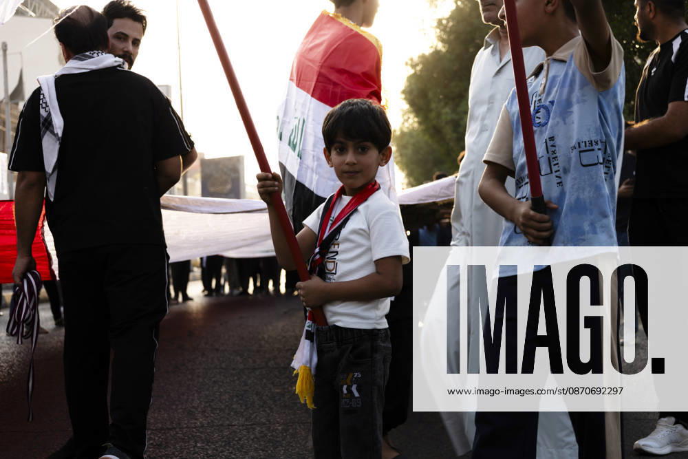 Najaf Iraq October Protest A child stands beside demonstrators carrying flags during a protest in Najaf, Iraq on October 25, 2026. The protest marked the seventh anniversary of the October 2019 protest movement, with participants calling for political reform, anti-corruption measures, improved public services and more jobs. Najaf Najaf Iraq