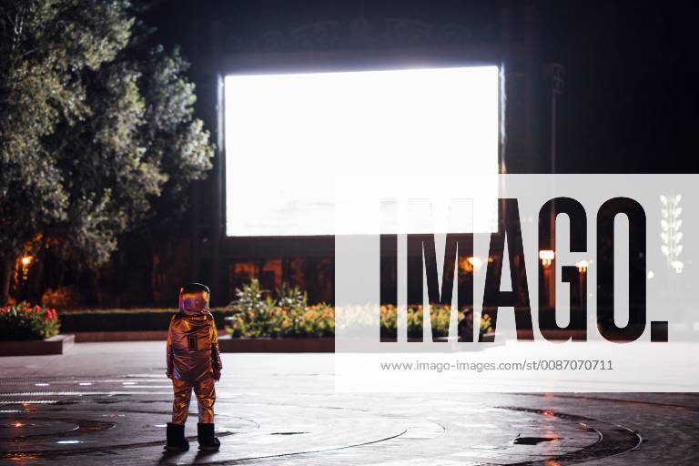 Spaceman on a square at night attracted by shining projection screen model released Symbolfoto VPIF00753