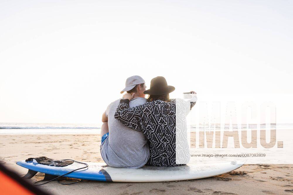 IMAGO Creative: Ende des Sommers Couple camping on the beach, taking smartphone selfies model released Symbolfoto UUF15155