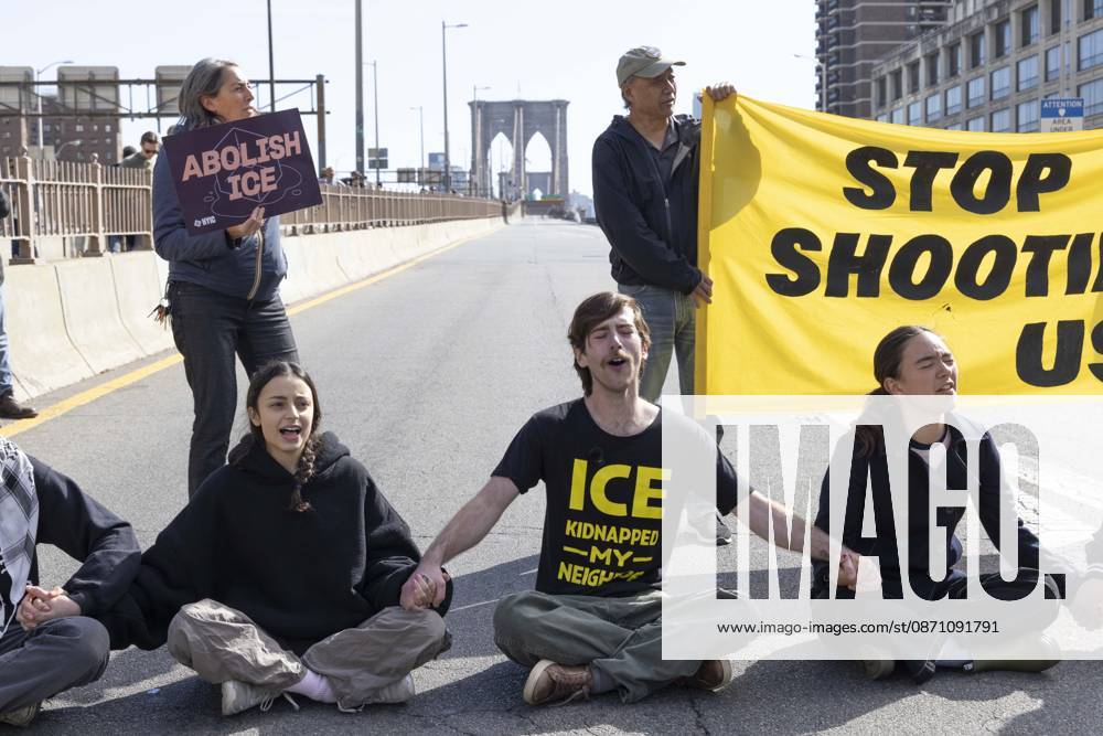 Anti-ICE (U.S. Immigration and Customs Enforcement) demonstrators sit in the roadway on the Brooklyn Bridge with a banner and signs that read STOP SHOOTING US ABOLISH ICE protesting the continued detainment of O. Belgal, who was shot by federal agents in the Bronx with his 5-yr-old son in the car. A protester wears a shirt that reads ICE KIDNAPPED MY NEIGHBOR. The demonstration stopped Brooklyn bound traffic and results in arrests by NYPD. Protesters call for ICE out of New York. New York USA - ZUMAr174 20261028_znp_r174_008