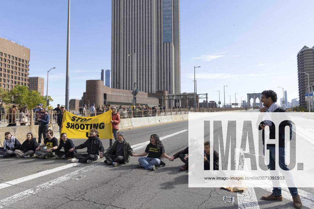 Anti-ICE (U.S. Immigration and Customs Enforcement) demonstrators sit in the roadway on the Brooklyn Bridge with a banner that reads STOP SHOOTING US protesting the continued detainment of O. Belgal, who was shot by federal agents in the Bronx with his 5-yr-old son in the car. The demonstration stopped Brooklyn bound traffic and results in arrests by NYPD. Protesters call for ICE out of New York. New York USA - ZUMAr174 20261028_znp_r174_012