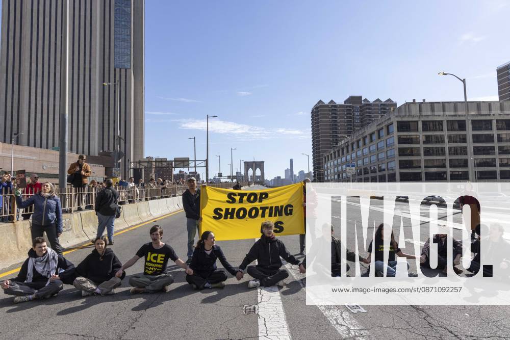 Anti-ICE (U.S. Immigration and Customs Enforcement) demonstrators sit in the roadway on the Brooklyn Bridge with a banner that reads STOP SHOOTING US protesting the continued detainment of O. Belgal, who was shot by federal agents in the Bronx with his 5-yr-old son in the car. The demonstration stopped Brooklyn bound traffic and results in arrests by NYPD. Protesters call for ICE out of New York. New York USA - ZUMAr174 20261028_znp_r174_007