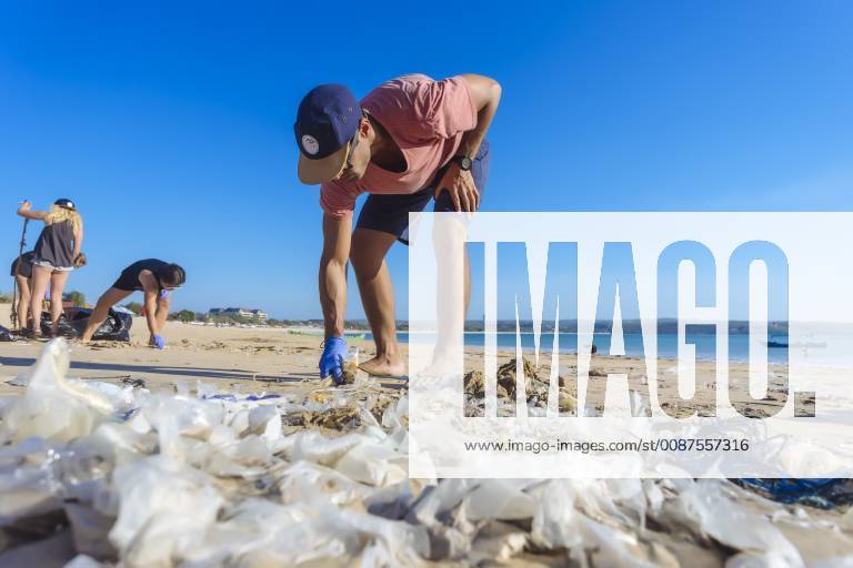 IMAGO Creative: Nächste Generation, Sozial- und klimabewusst Man bending while picking up trash at beach, Jimbaran, Bali, Indonesia, Jimbaran Bali Indonesia