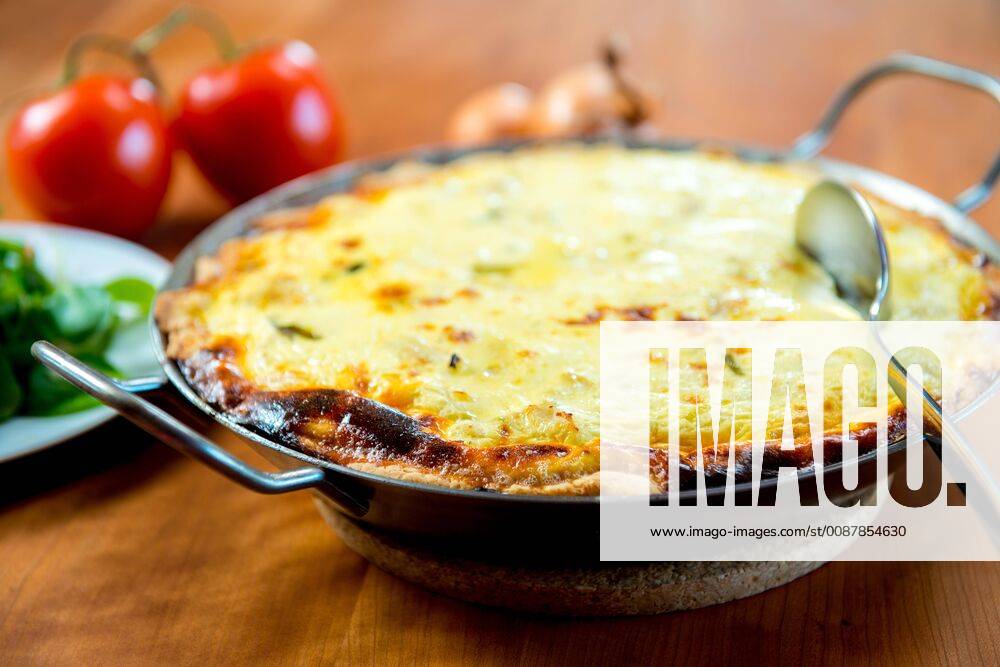 Baked quiche with field salad on wooden table