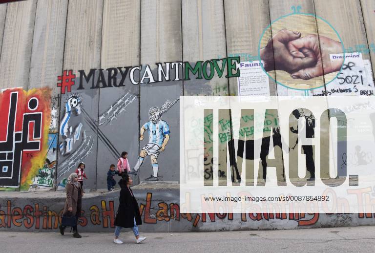 Palestinians walk past the Israeli Separation Wall in Bethlehem, West Bank, December 22, 2018. All the hotels in Bethlehem are fully booked for Christmas Eve. JER2018122201