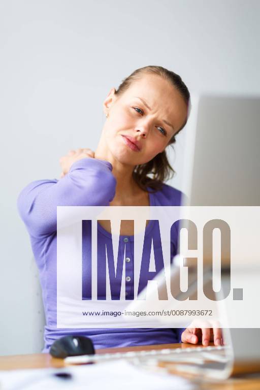 Working too hard - young woman working on a computer at an office, having sore back, being overloaded with work, sitting too much, putting too much stress on her eyes,.. model released Symbolfoto