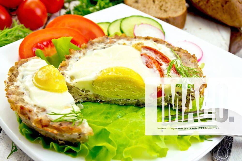 Tartlet meat with egg cut and vegetables on light board