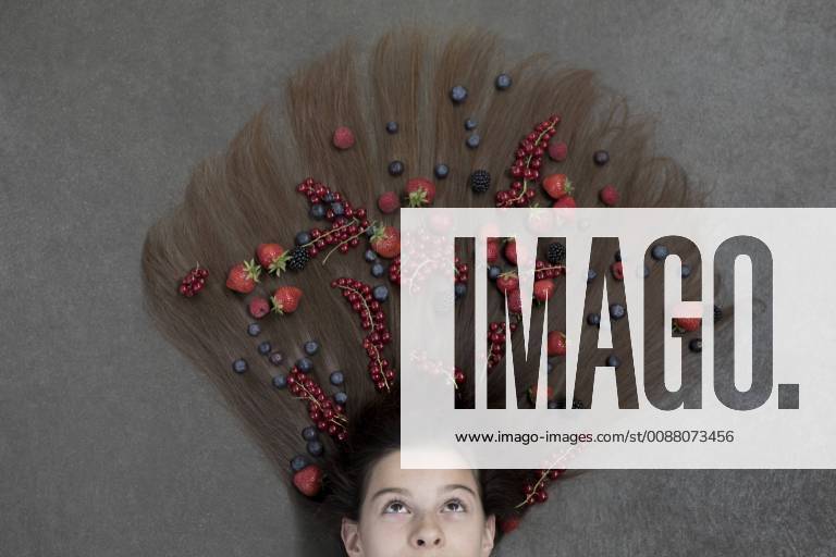 Portrait of girl lying on floor with fruits on hair looking up model released Symbolfoto PSTF00219