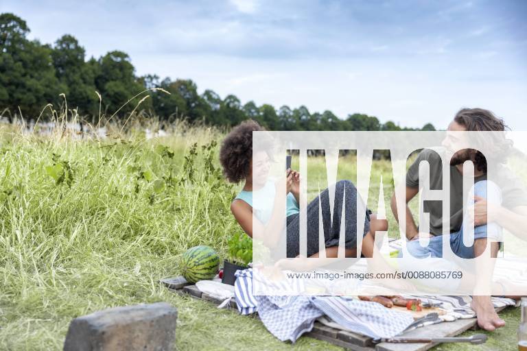 Happy couple having a barbecue and taking cell phone pictures in the nature model released Symbolfoto FMKF05288