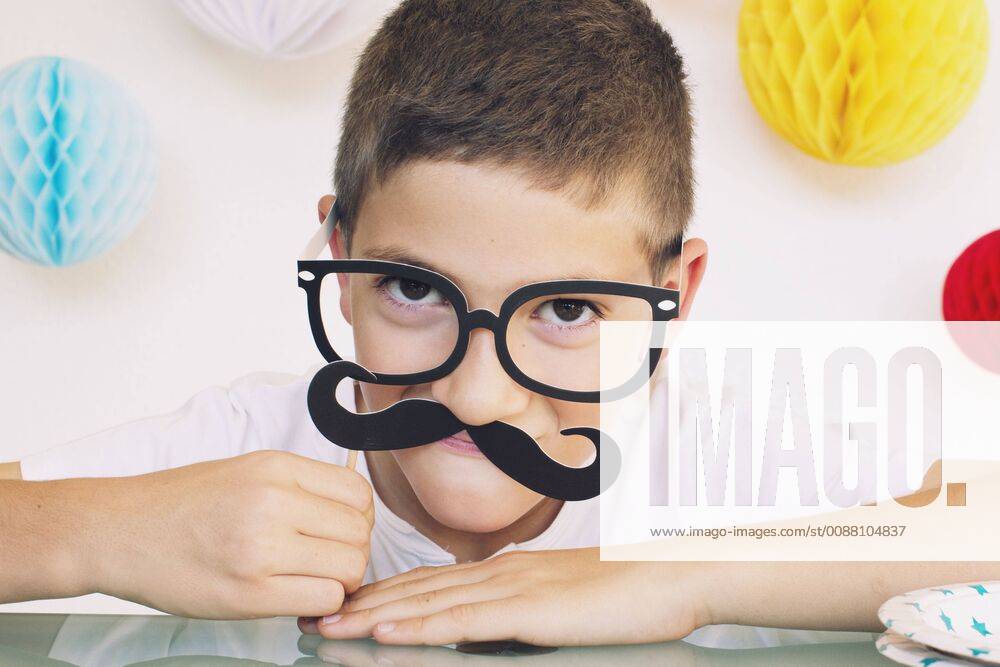 Boy wearing fake mustache and glasses at a birthday party