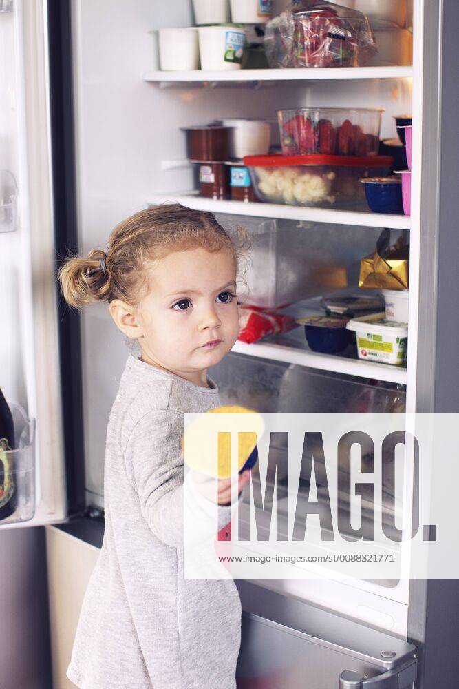 Little girl taking food out of refrigerator
