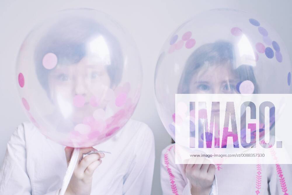 Children hiding behind transparent balloons