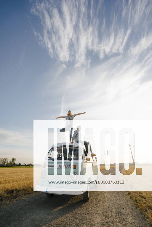 Young couple on roof of a camper van in rural landscape model released Symbolfoto GUSF01439