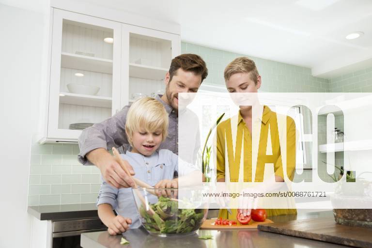 Smiling family preparing salad in kitchen together model released Symbolfoto property released MFRF01071