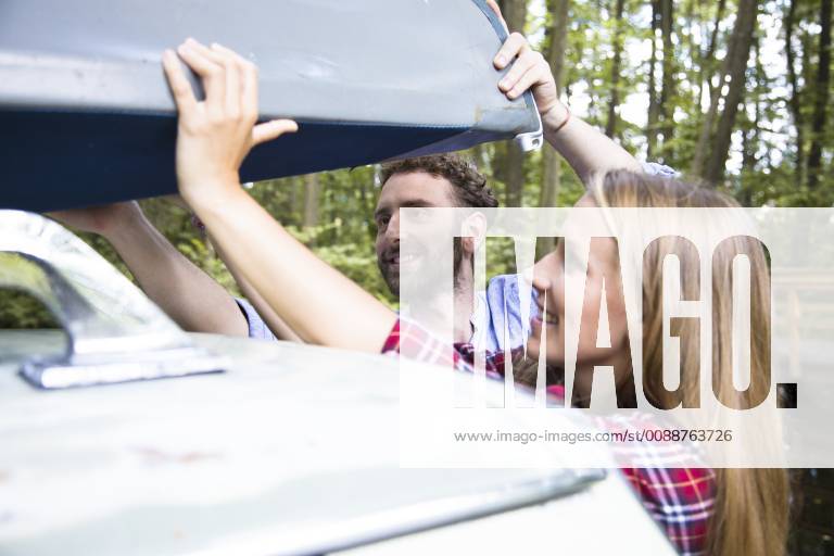 Smiling young couple taking canoe from car roof model released Symbolfoto FKF02803