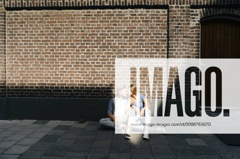 IMAGO Creative, Sommer, Schatten-Plätze bei Hitze Netherlands, Maastricht, young couple having a break in the city sitting on sidewalk model released Symbolfoto GUSF01502