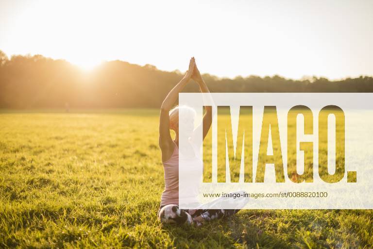 Senior woman doing yoga on rural meadow at sunset model released Symbolfoto DIGF05471