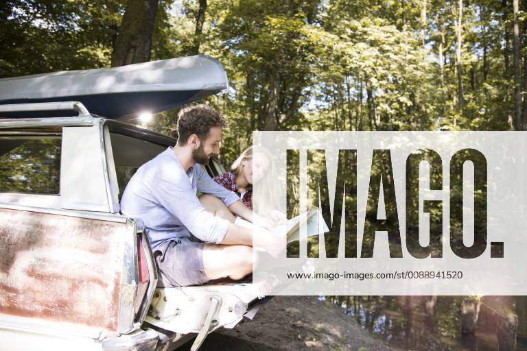 Smiling young couple with map and canoe in car at a brook model released Symbolfoto FKF02795