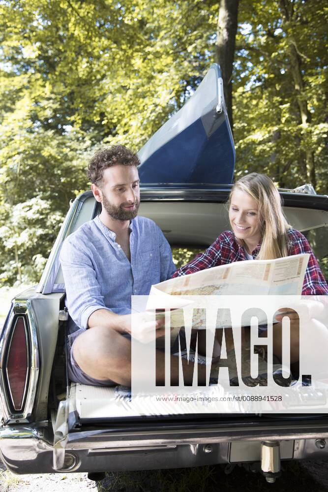 Smiling young couple with map and canoe in car at a brook model released Symbolfoto FKF02799